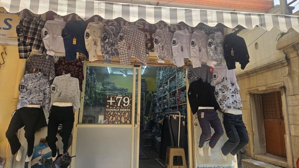 Rajeshwari Garments shop front in Santhusapet with +79 casual shirts displayed above the door